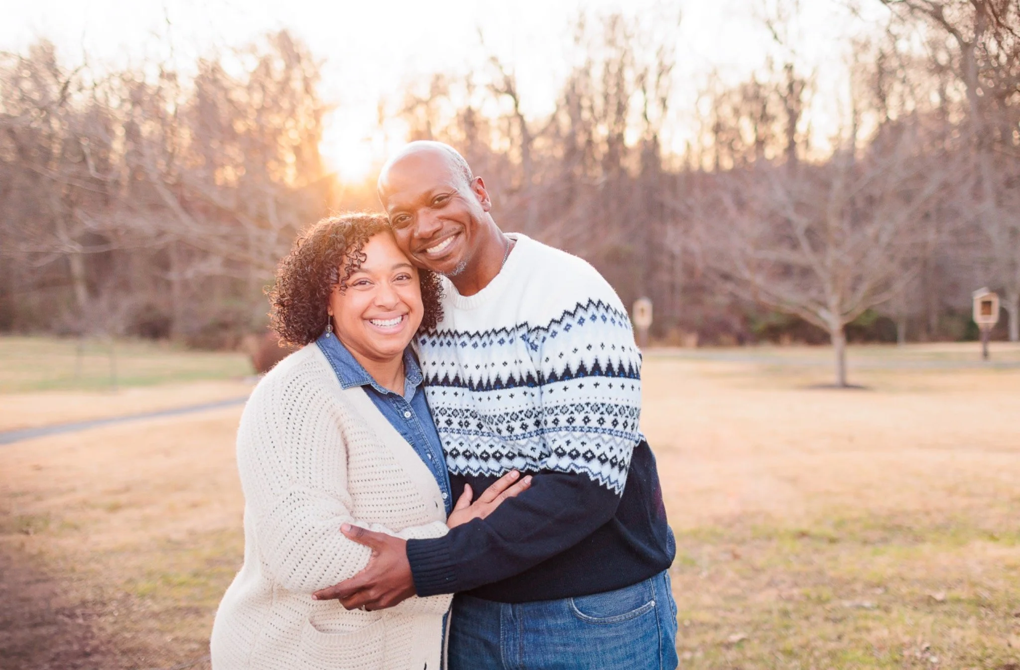 Couple embracing with golden sun behind them at the Shrine of St. Anthony in Clarksville, Maryland.