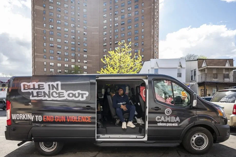 A van with the cure-violence group “Brownsville In Violence Out” sits near the intersection of Sutter Avenue and Mother Gaston Boulevard as the Langston Hughes Houses tower in the background, on Friday, Apr. 30, 2021.  Hiram Alejandro Durán/THE CITY