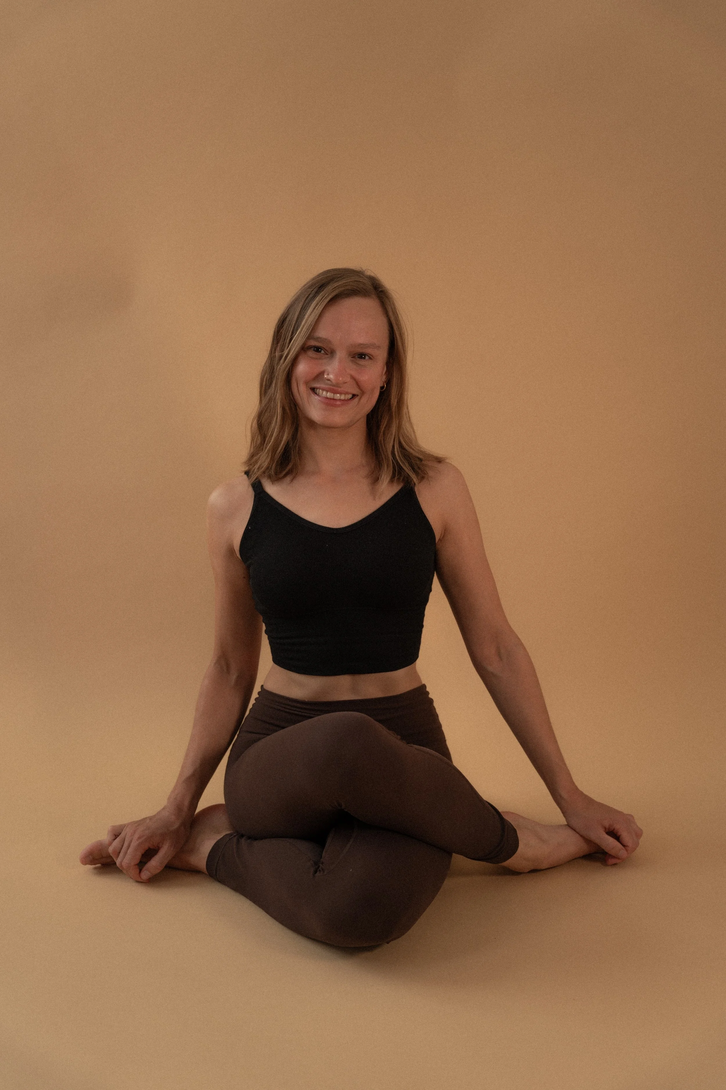 Lächelnde Frau, die mit überschlagenen Knien auf dem Boden sitzt.