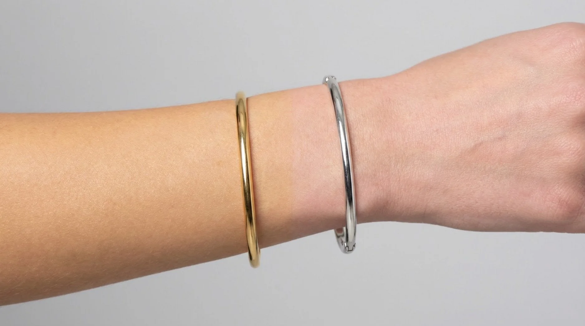 Side-by-side comparison of a woman's wrist showing gold and silver bracelets to demonstrate the jewellery test for skin undertones.