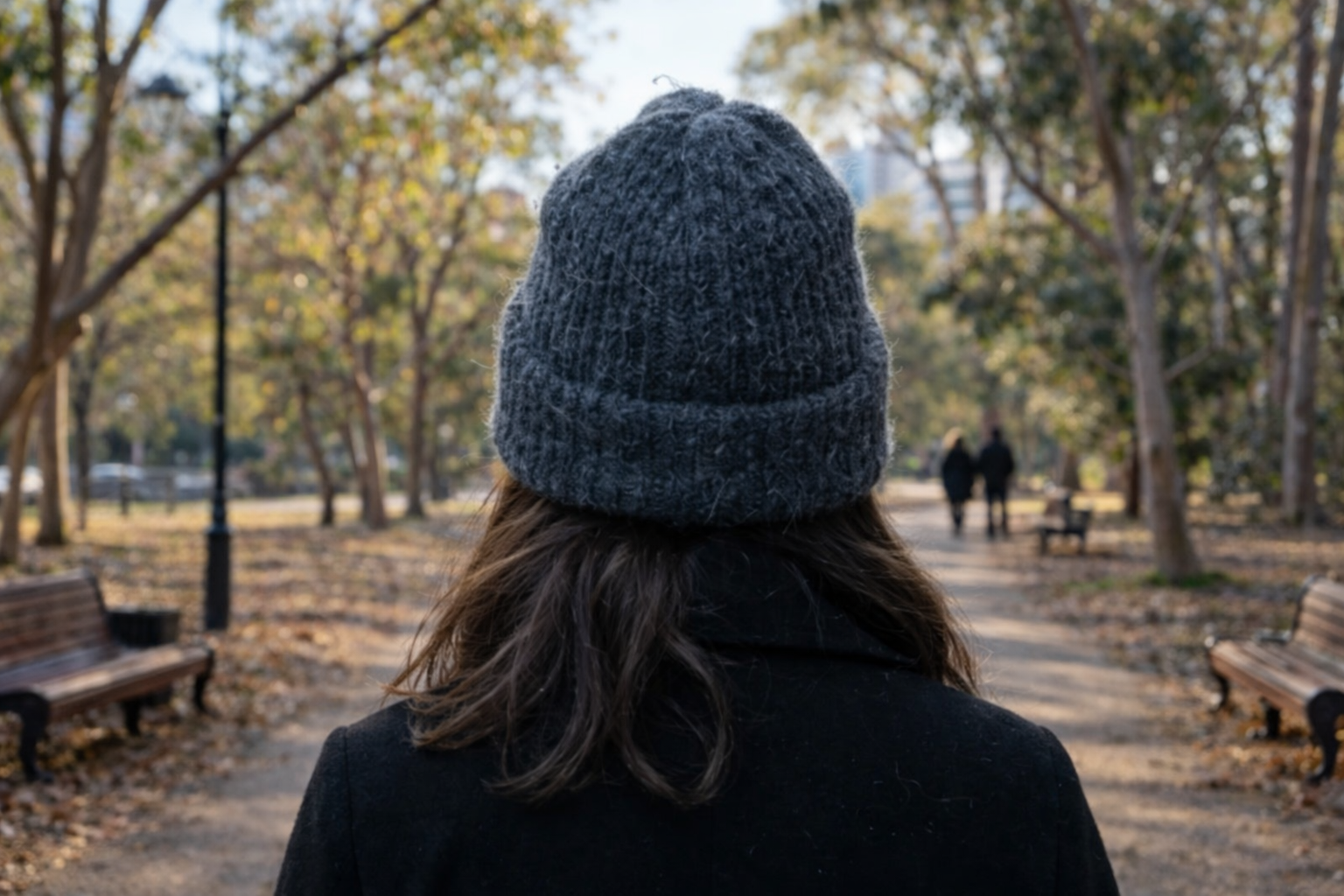 Woman wearing a grey beanie walking through a city park during a mild winter day in Sydney