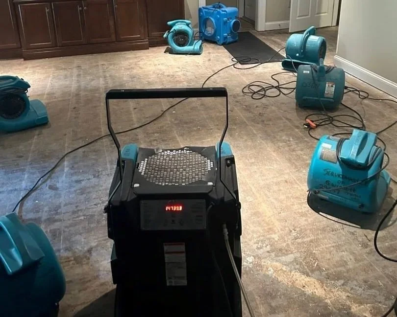 Air movers, air scrubber and dehumidifier set by ServiceMaster to dry basement living room