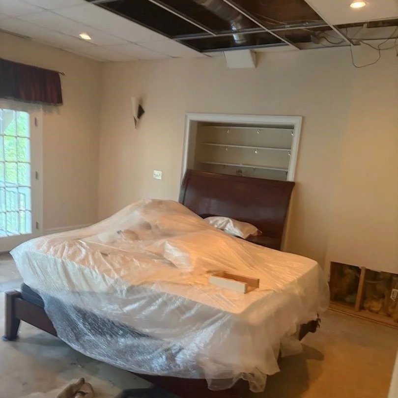 Basement bedroom with damaged ceiling tiles, drywall and carpet removed