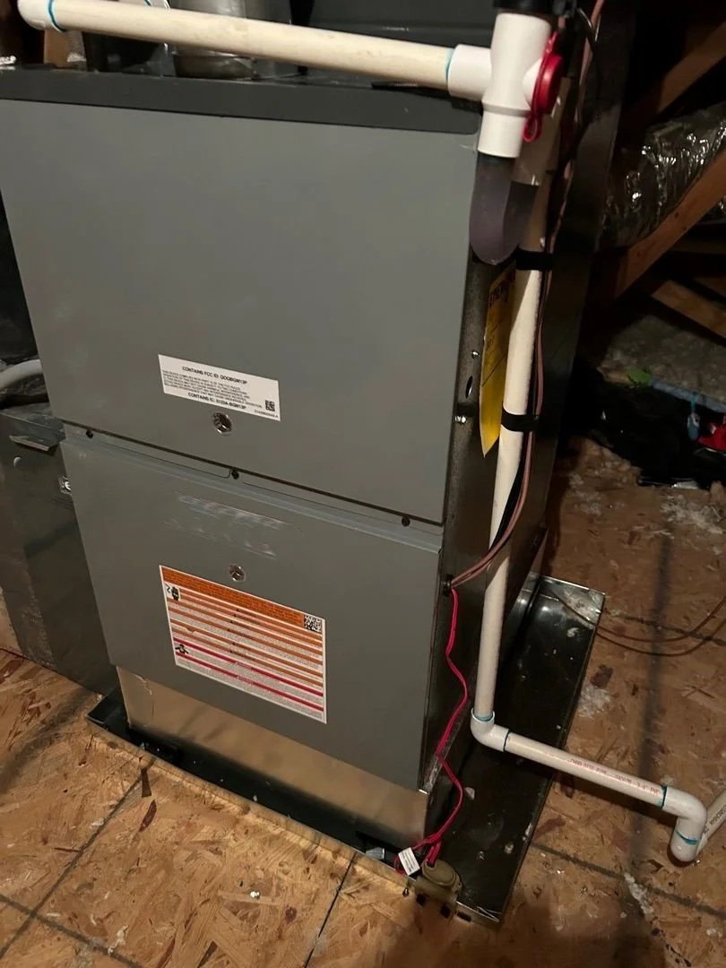 HVAC unit in drip pan with PVC drain pipe on right side and vertical port on top