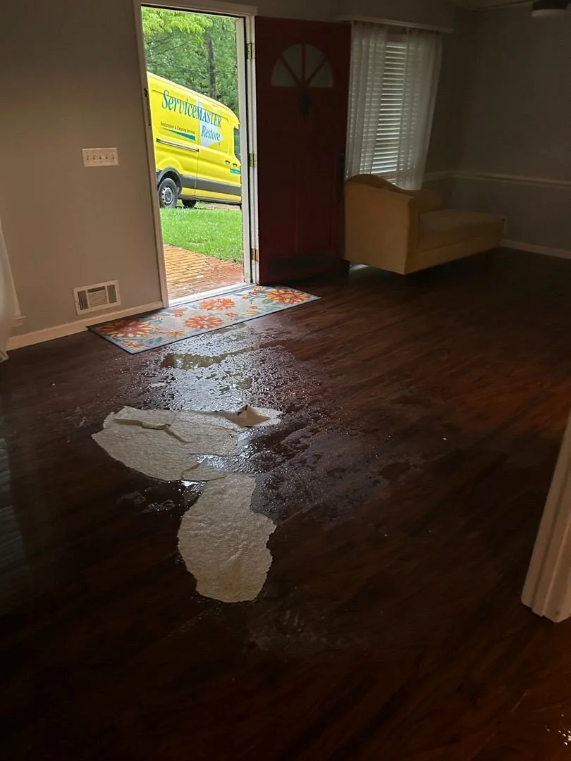 ServiceMaster 5 Points van visible through front door of home with water damage and ceiling drywall on floor inside