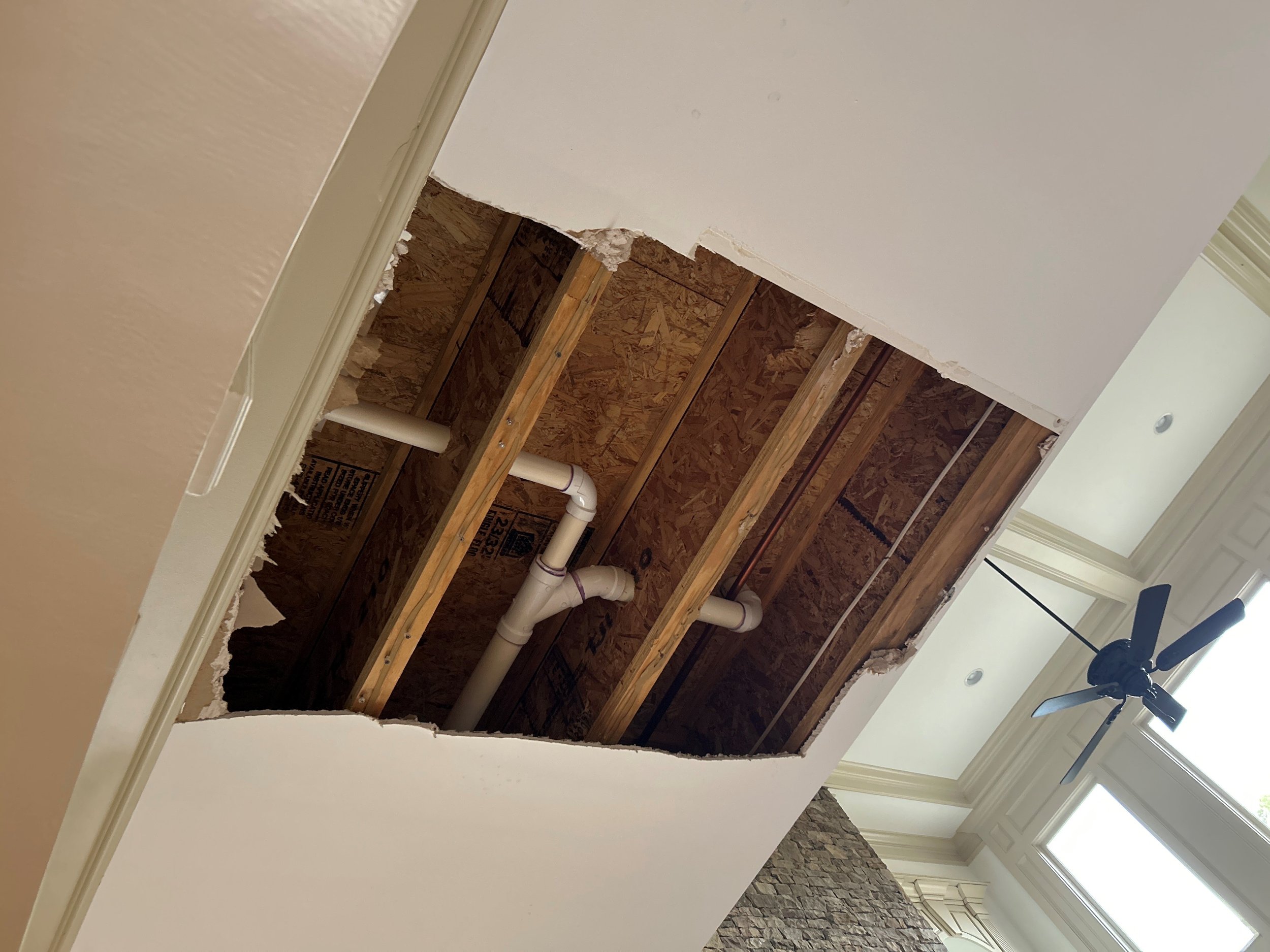 Damaged drywall removed by ServiceMaster from living room ceiling after 2nd floor bathtub overflow