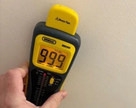 Moisture meter reading drywall on ceiling of kitchen after water damage