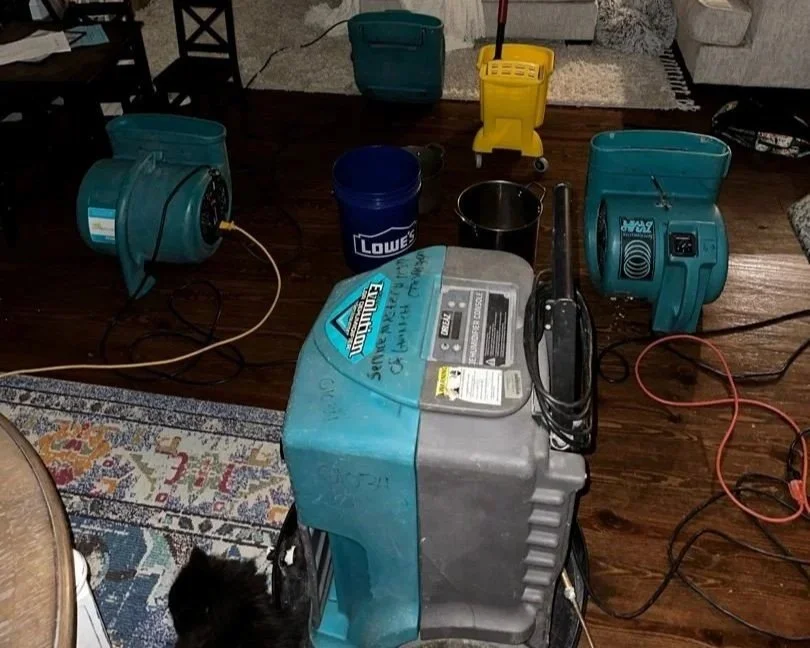 ServiceMaster air movers and dehumidifier set to dry the living room ceiling and floor after a 2nd floor toilet tank cracked.