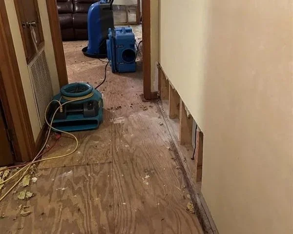 Damaged carpet and drywall removed with drying equipment set to dry hallway