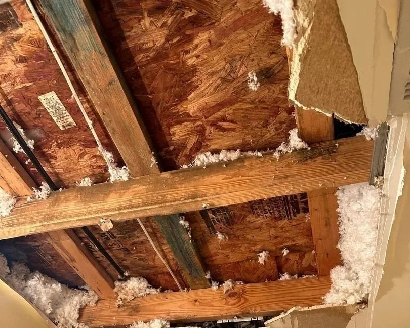 Affected bathroom ceiling after drywall fell due to saturation from an attic HVAC leak