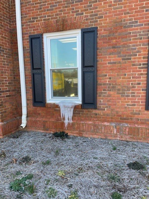 Ice dam formed from water flowing out of a ground floor window during a freeze