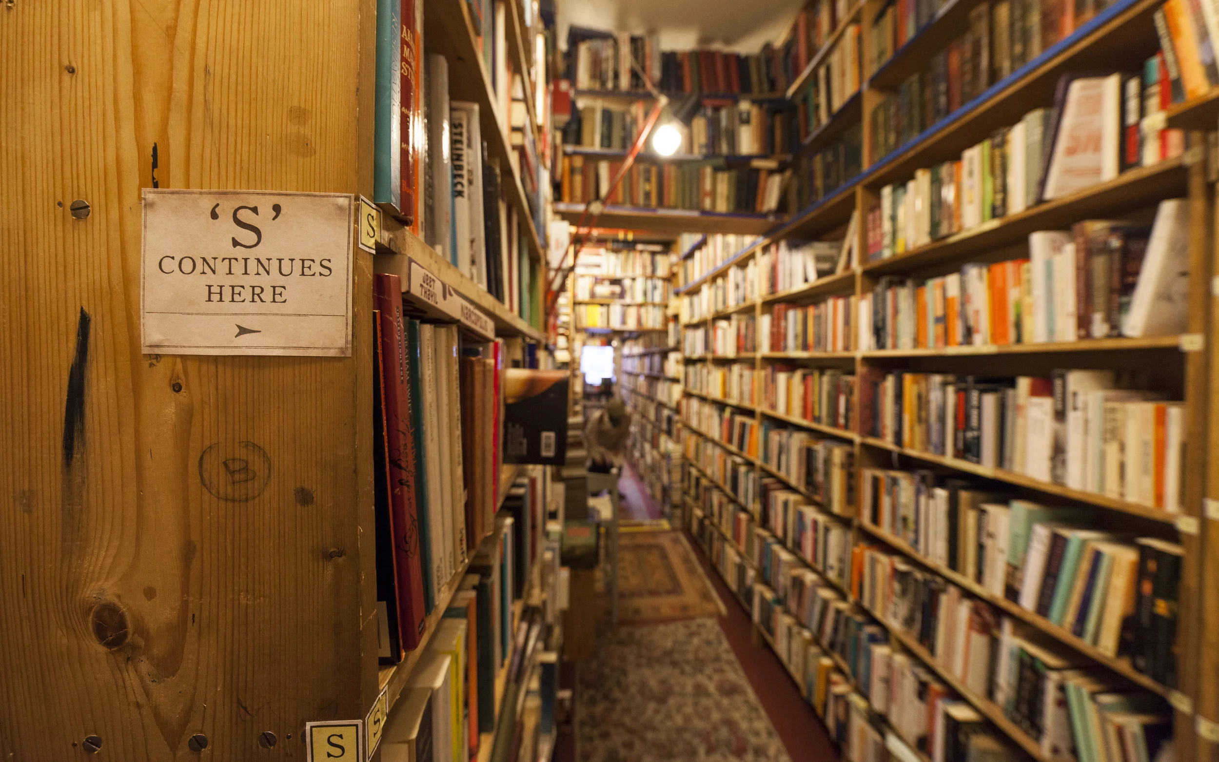 Armchair Books, natural woods bookshelves with rolling ladders and books stacked to the ceiling. 