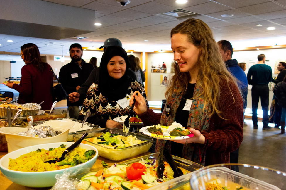 Maryam Yousefi ( New Roots and PhotoVoice Participant ) and Melissa Katz ( CLAS ‘19 ) sample food cooked by the participants, representing cuisines from Afghanistan, Bhutan, and the Democratic Republic of Congo.