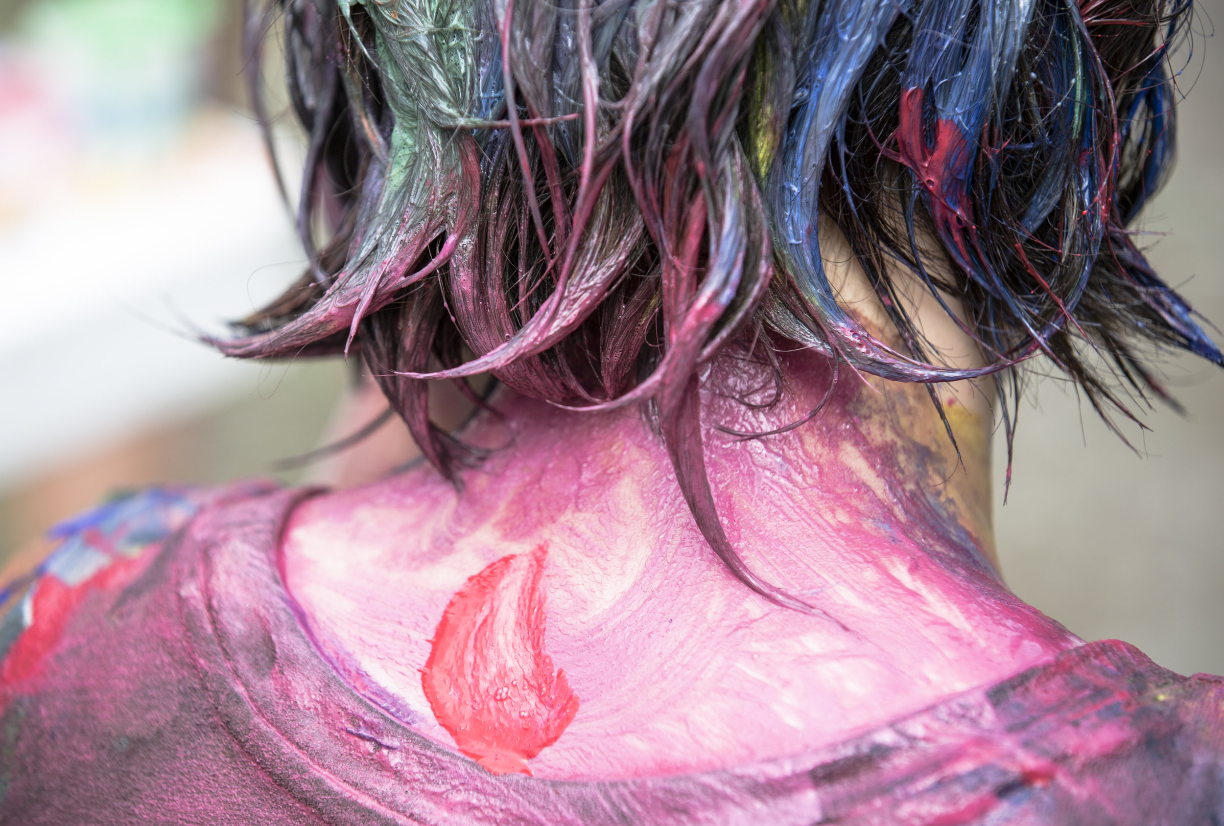  A teen camper is covered in paint during their art gallery activity. 