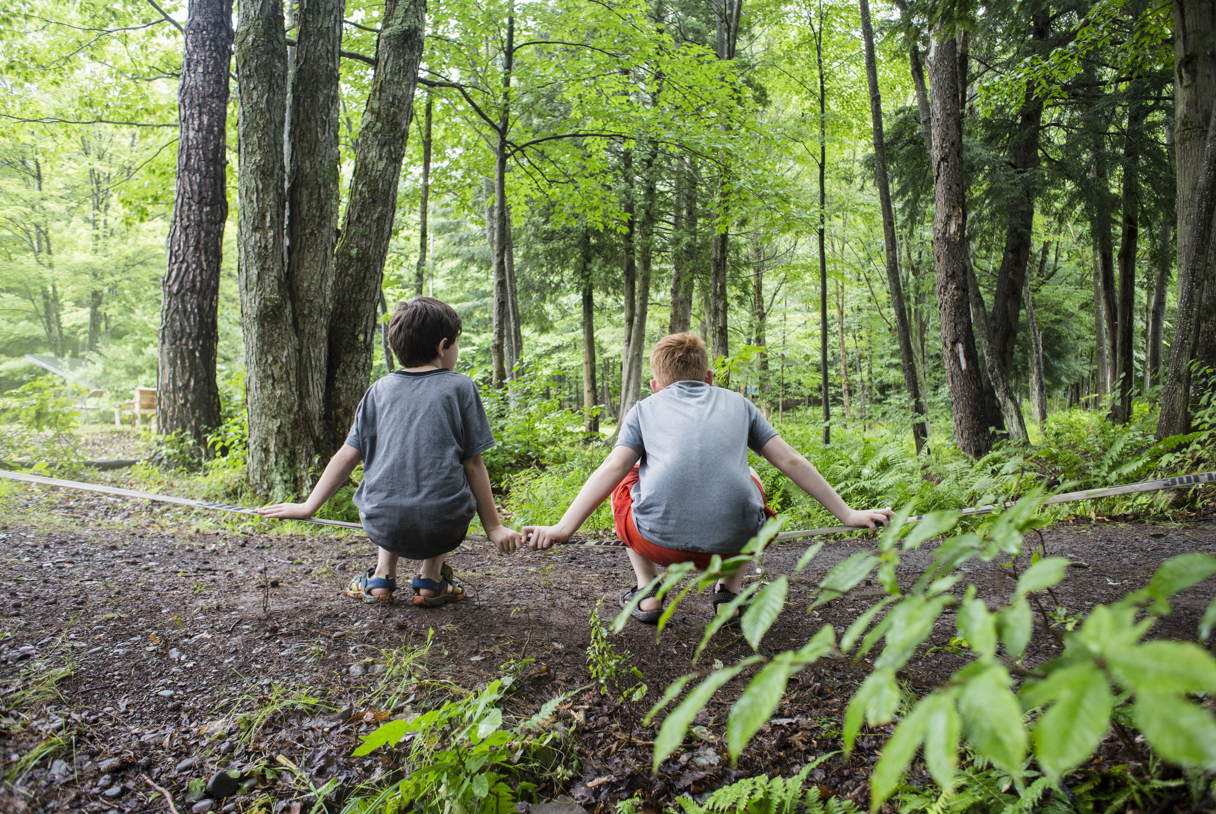  Campers sit on a slack-line in the grove. 