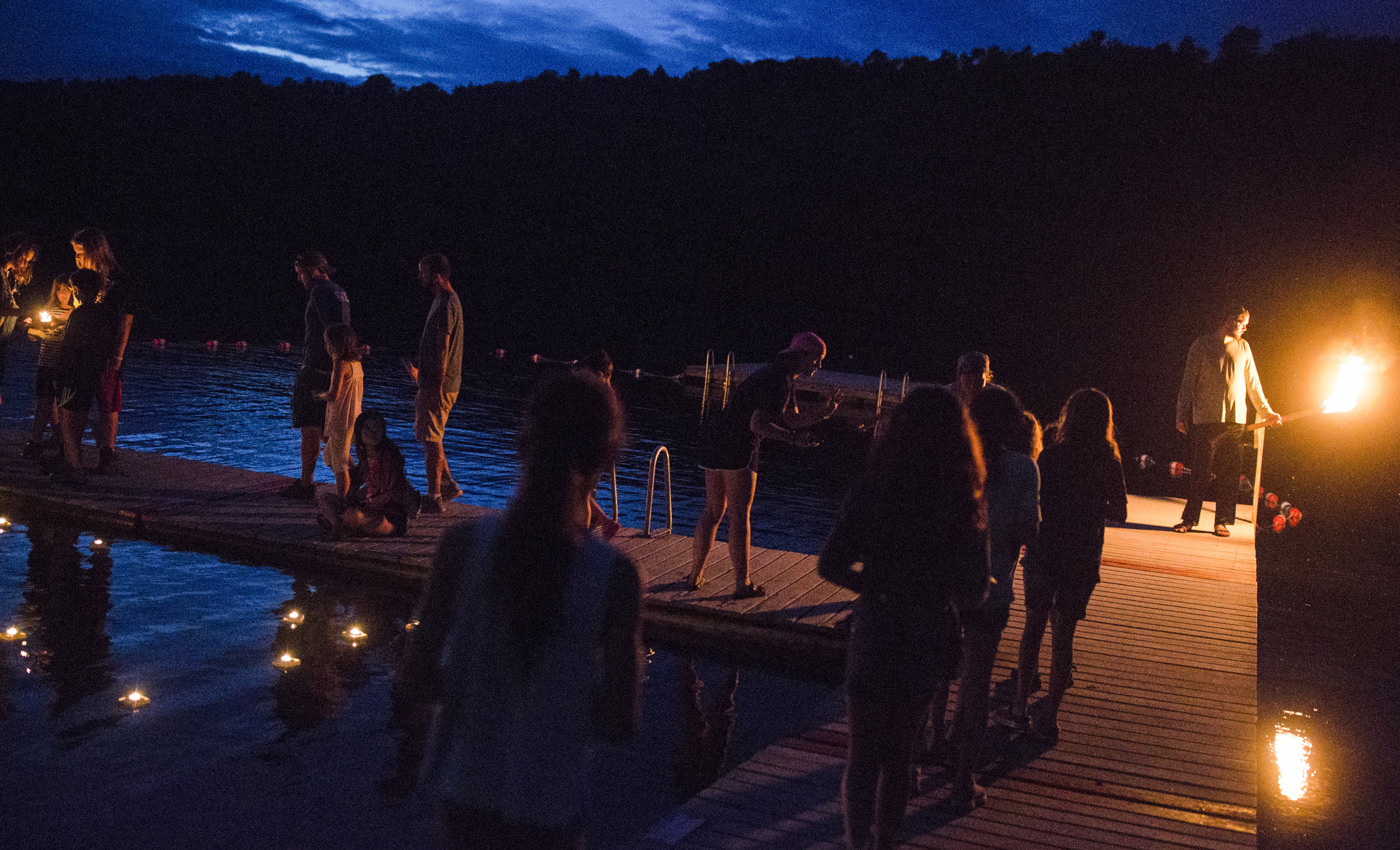  Staff members help campers light candles for the wish boats during the closing ceremony at the end of the week. 