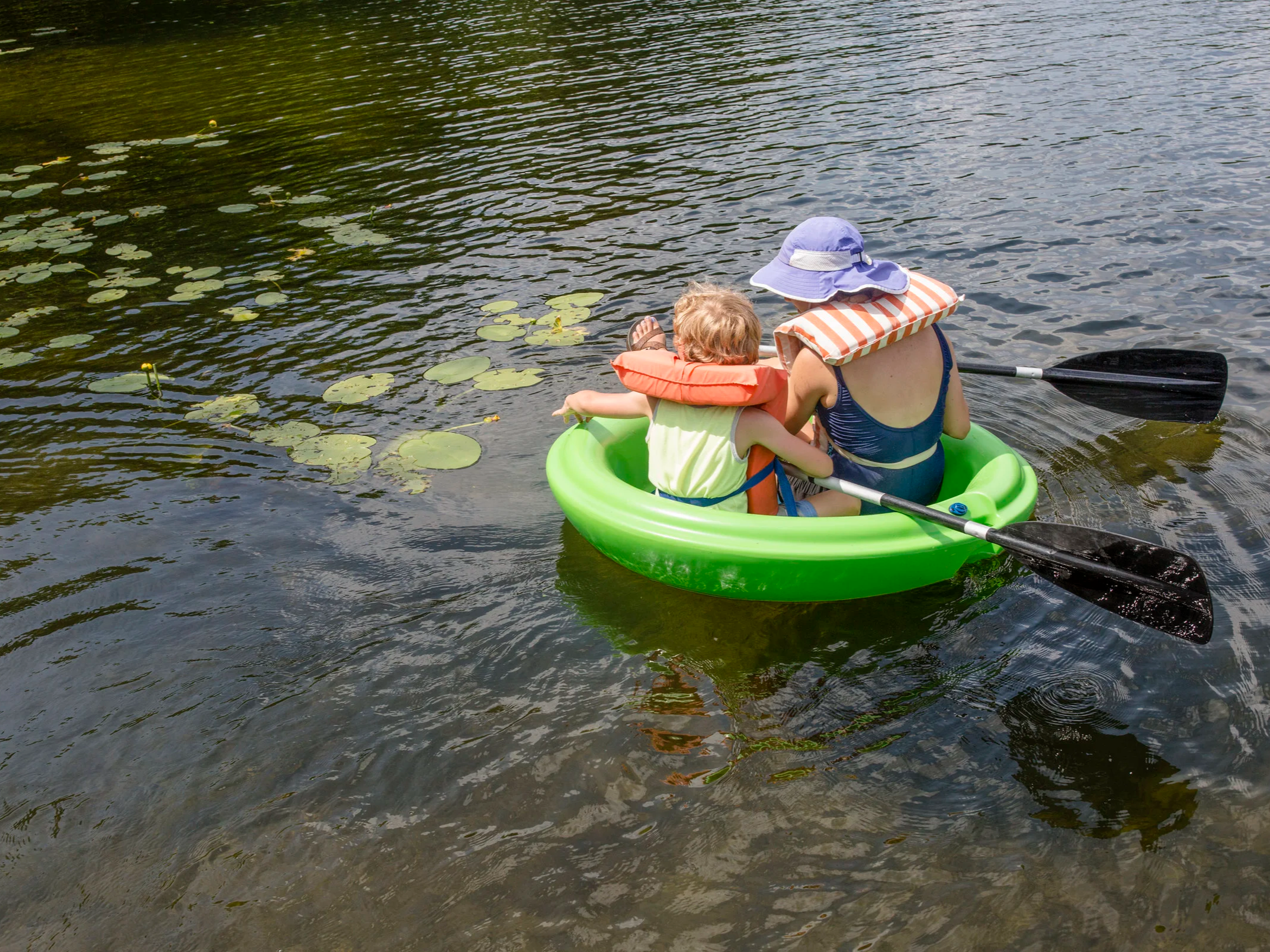 A woman and a child paddle a corcl boat on a lake in Upstate New York