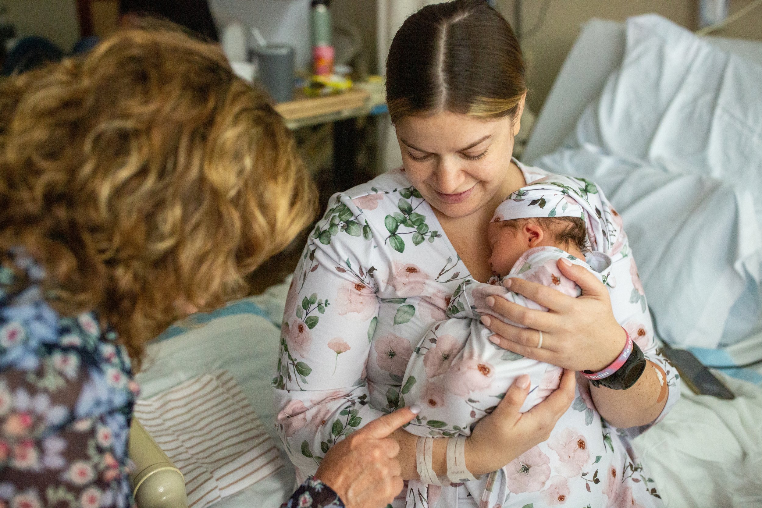 A new mom holds her baby in the hospital as her mother visits
