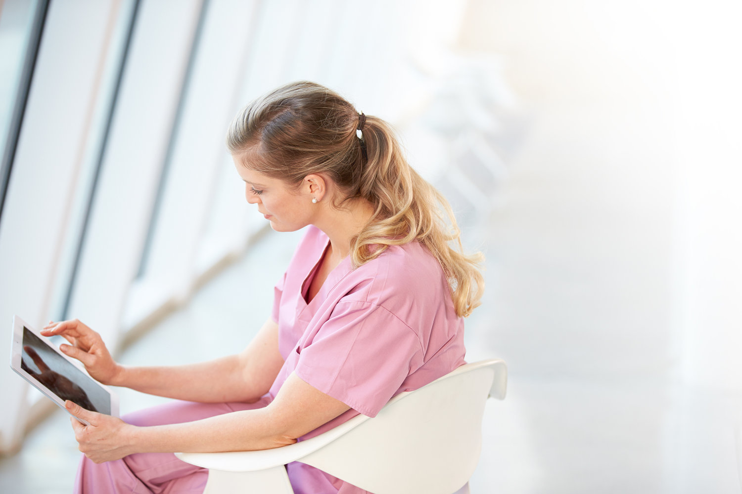 female-nurse-sitting-in-chair-using-digital-PF68SDD.jpg
