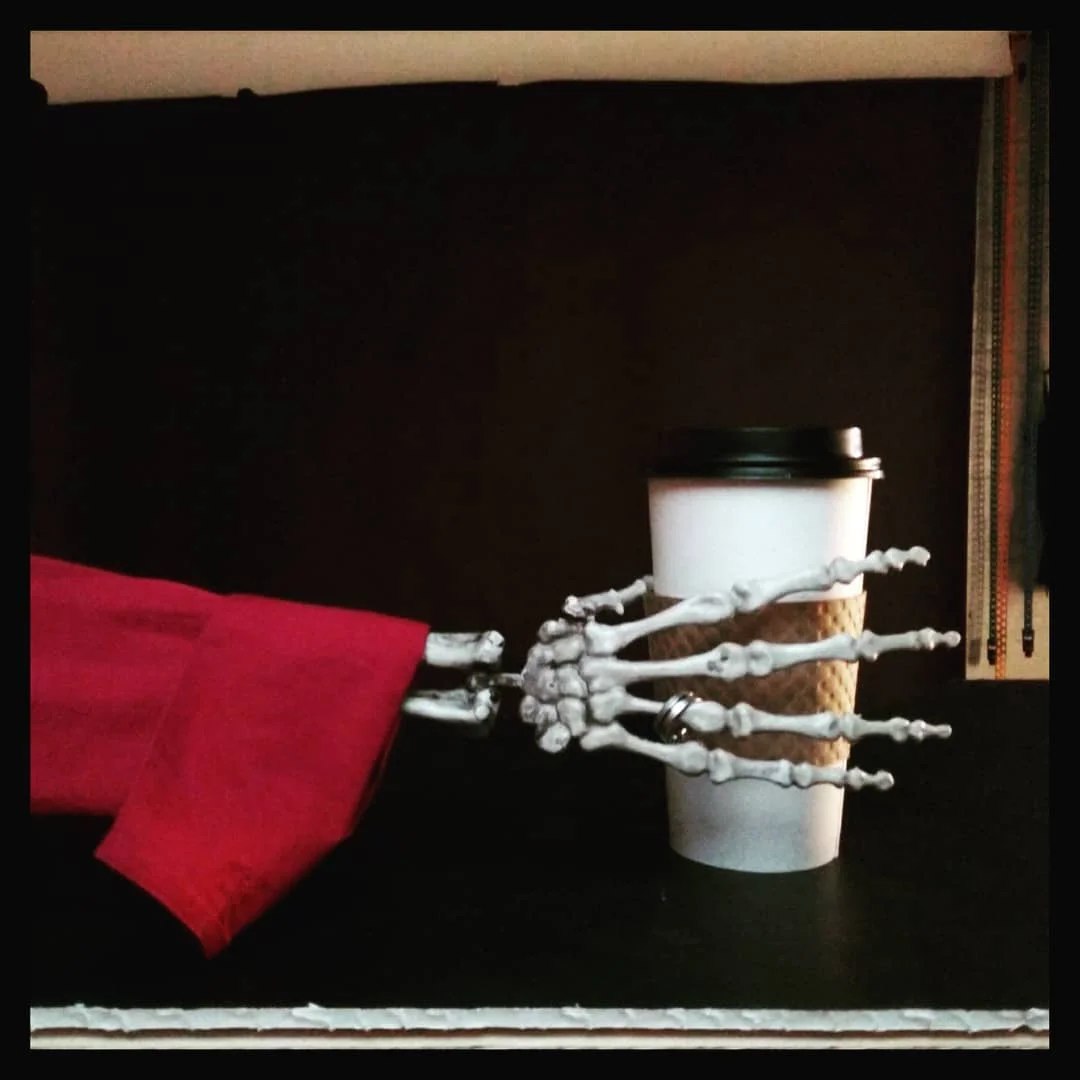 a cell-phone shot showing how we setup the image above. Simple and clean; shooting everything on black and using the color red both in clothing and items, but also with subtle red rim lighting to help separate things from the deep black background. Weather brought everything; the shirt, the ring, the coffee cup and the gulp! skeleton arm!
