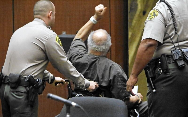 Samuel Little, raises his arm in defiance leaving court (Al Seib, Los Angeles Times)
