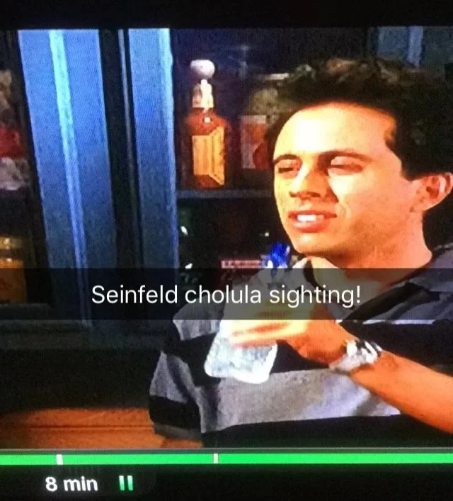 Screenshot of Jerry Seinfeld from the show Seinfeld with a bottle of Cholula hot sauce
