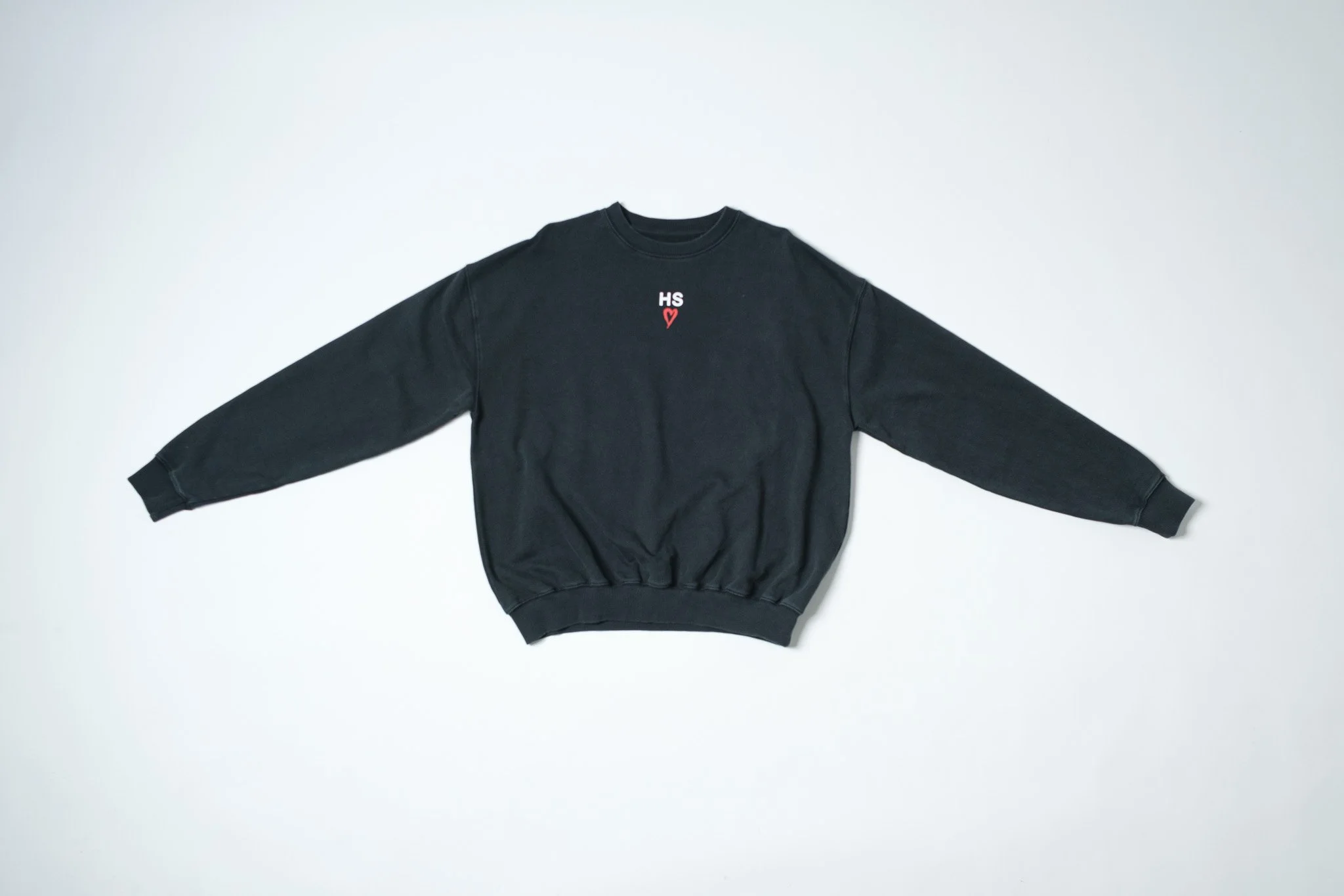 Black sweatshirt with 'HS' and a red heart embroidered on the chest, laid flat on a white background.
