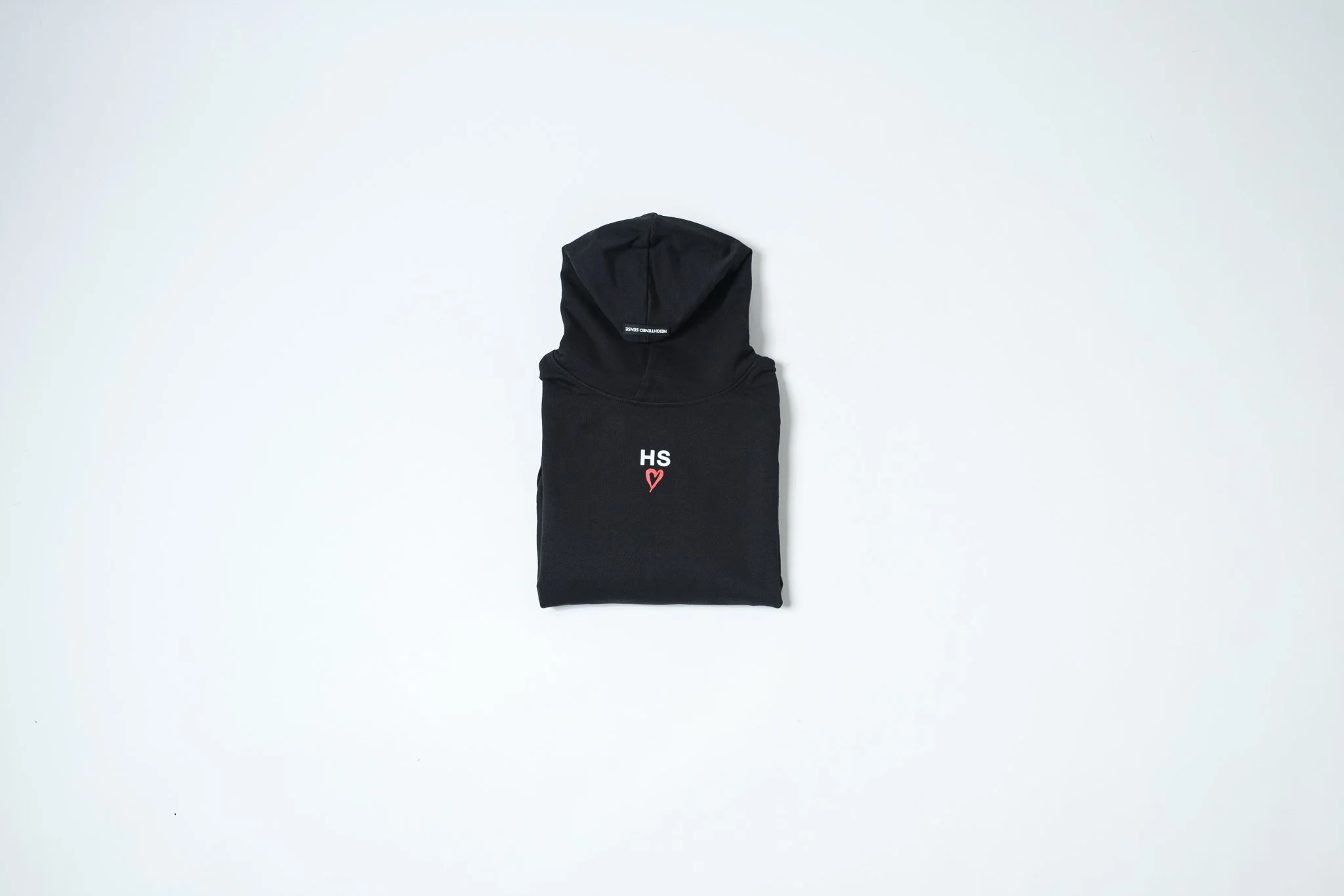 A black hoodie with the letters 'HS' and a small red heart on the front, laid flat against a white background.