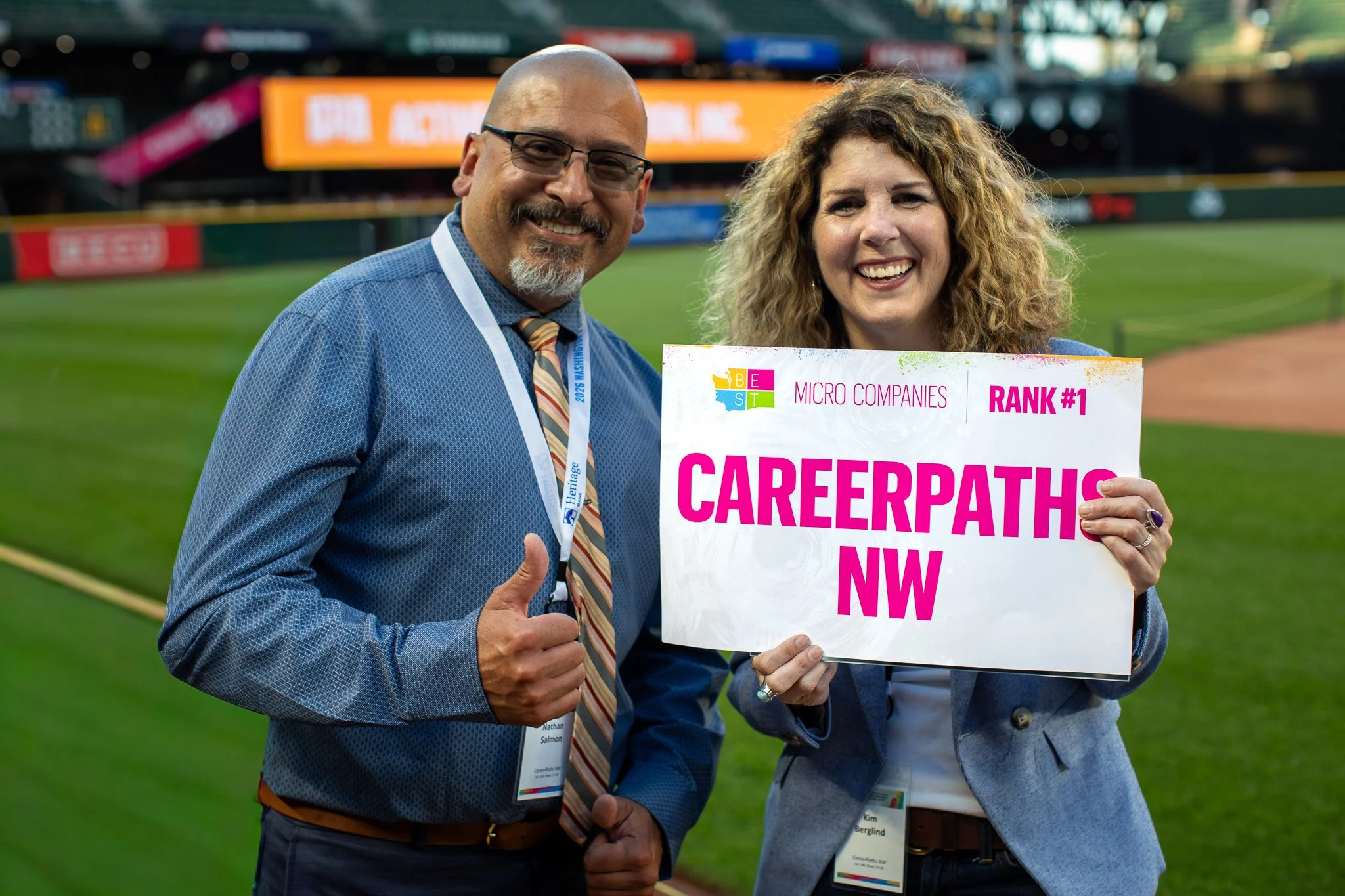Two CareerPaths NW team members holding a CareerPaths NW sign on the field at the Puget Sound Business Journal awards