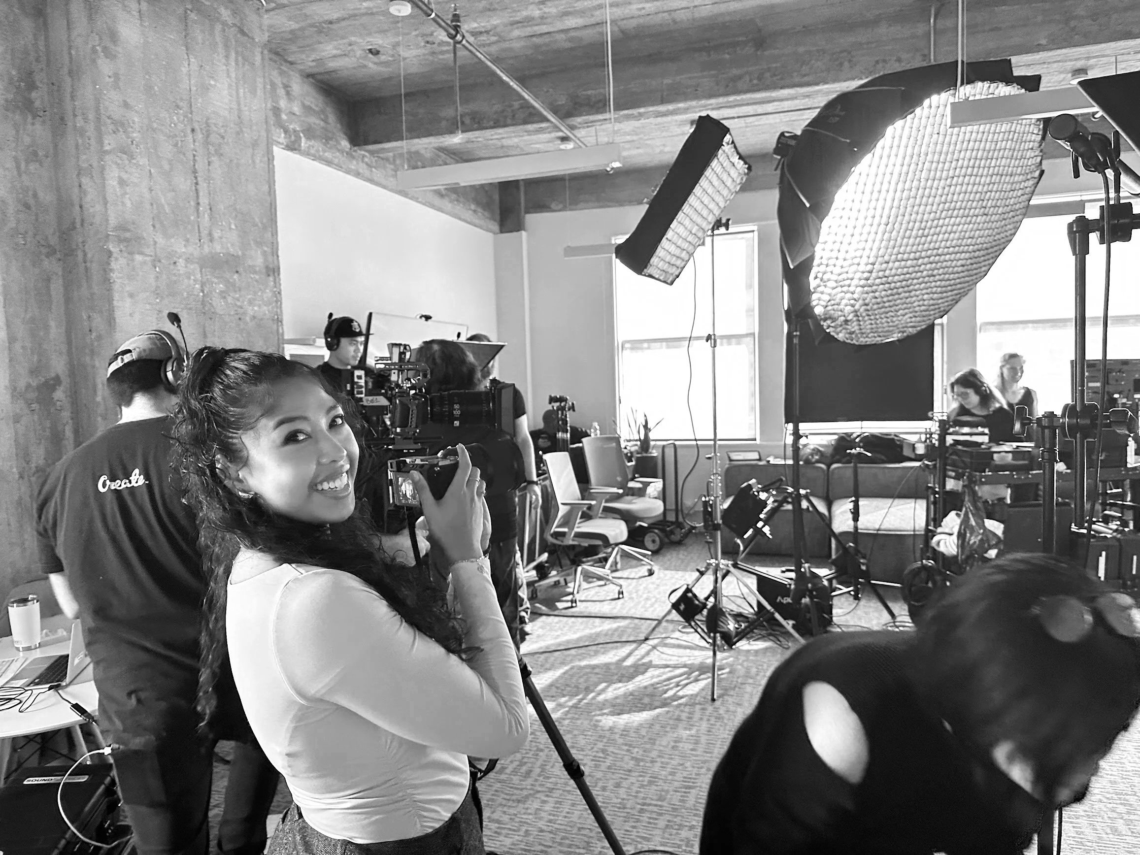 Behind the scenes on a Standing Sideways shoot, with a camera operator smiling on a busy office set
