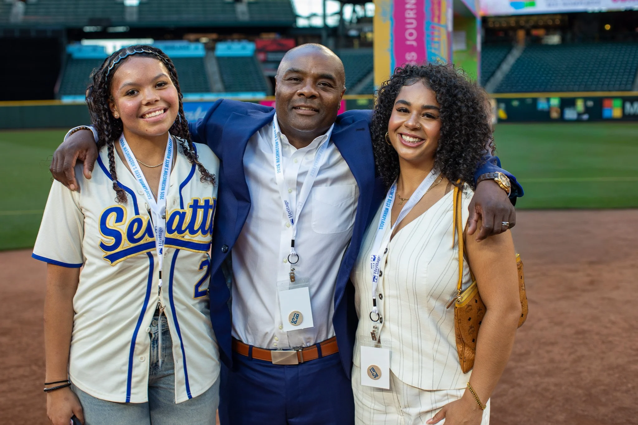 A man in a suit with two guests in Seattle baseball jerseys at the Puget Sound Business Journal awards