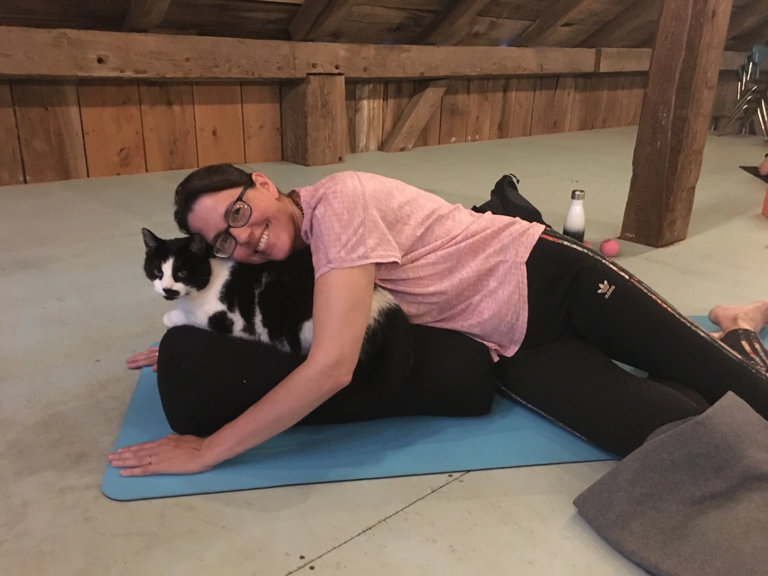 Susanne shares her bolster and a snuggle with Moustache during Restorative Yoga.