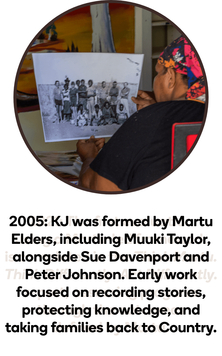 Martu person holding a black and white archival photograph, representing KJ's early work in 2005 recording stories and protecting Martu cultural knowledge