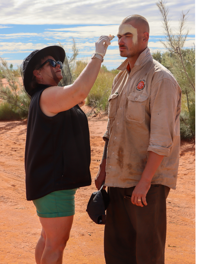 Sharon prepares Martu Support Officer James with special effects makeup.png