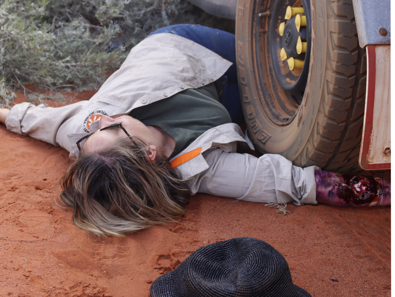 Martu Support Coordinator Kate lays injured under the back tyre.png