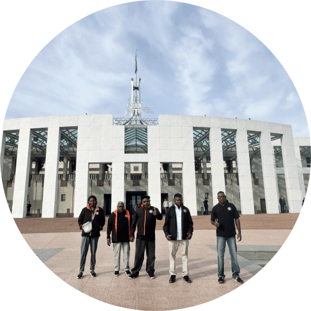 Group of Martu standing in front of Parliament House in Canberra, representing KJ's advocacy work and community-led approach to partnership and change