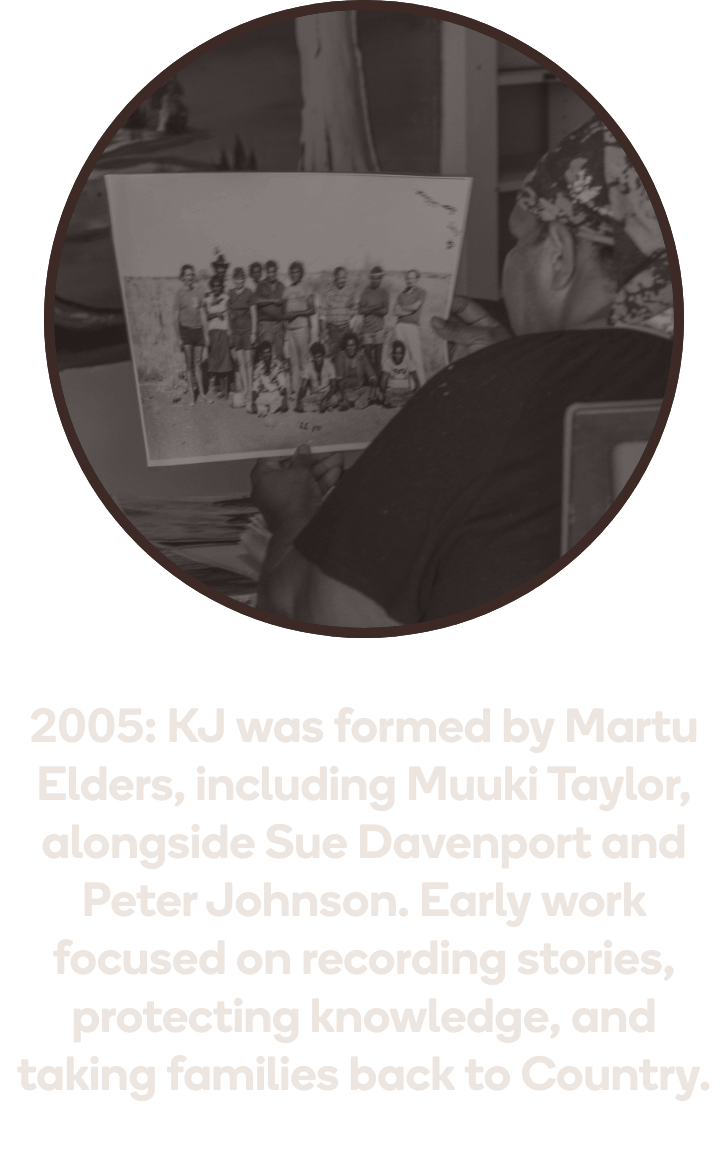 Martu person holding a black and white archival photograph, representing KJ's early work in 2005 recording stories and protecting Martu cultural knowledge
