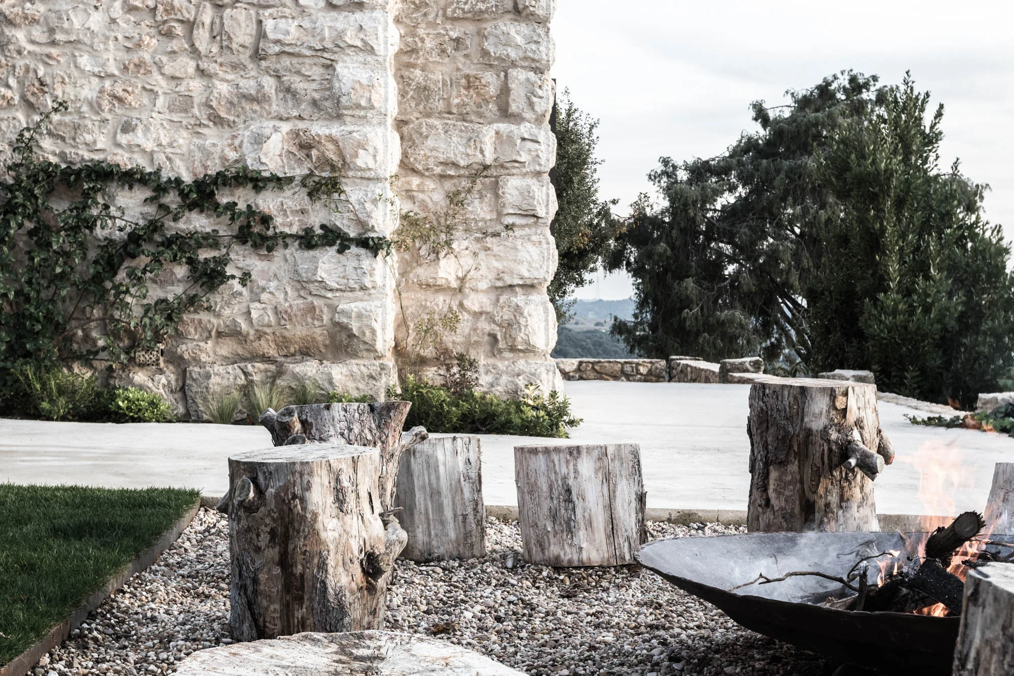 Jardín con troncos y zona de hoguera diseñada por Locus Landscape Architecture