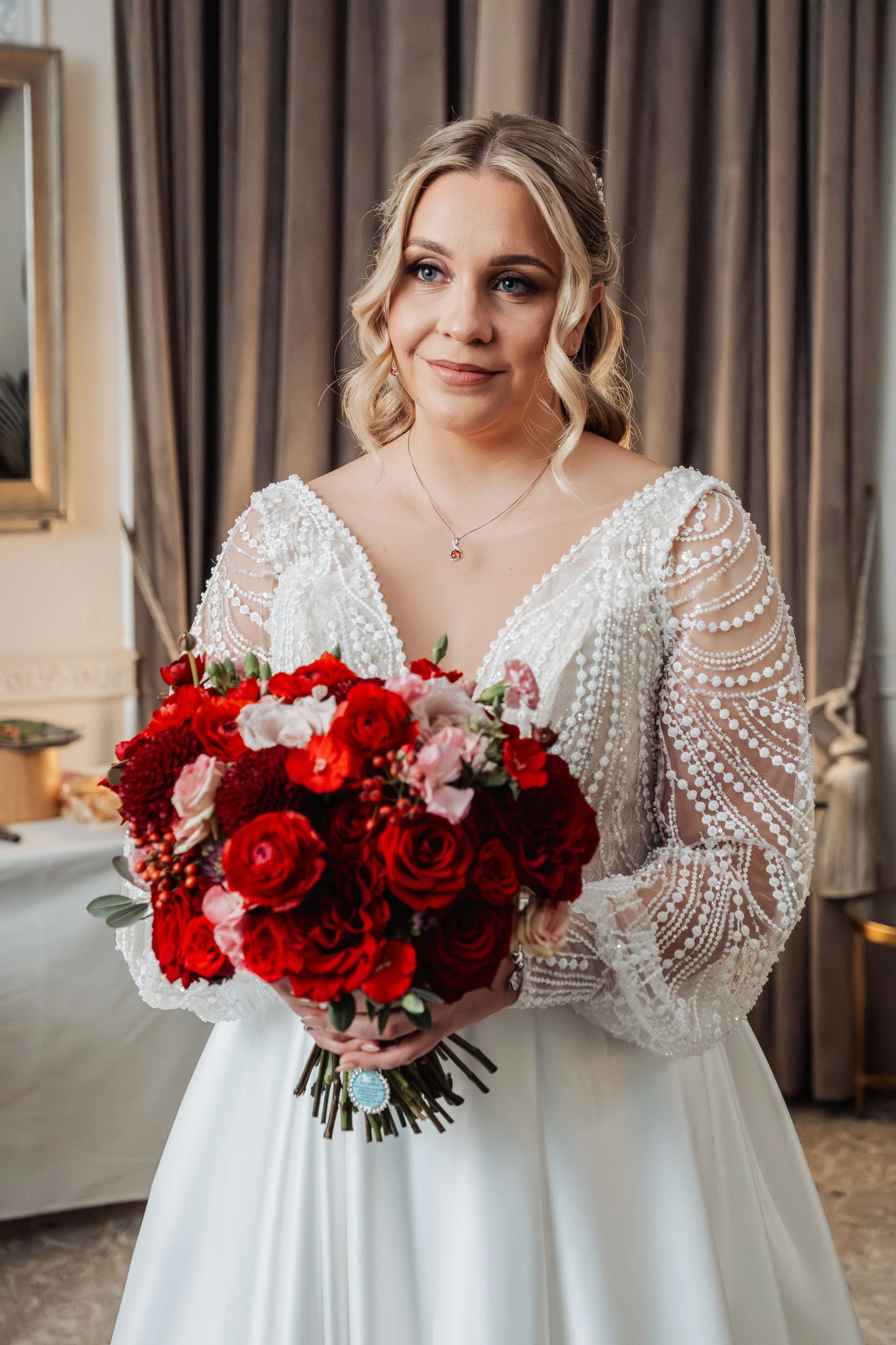 The beautiful bride at Hensol Castle is stood holding her beautiful bouquet full of seasonal blooms in burgundy, red and rose colours