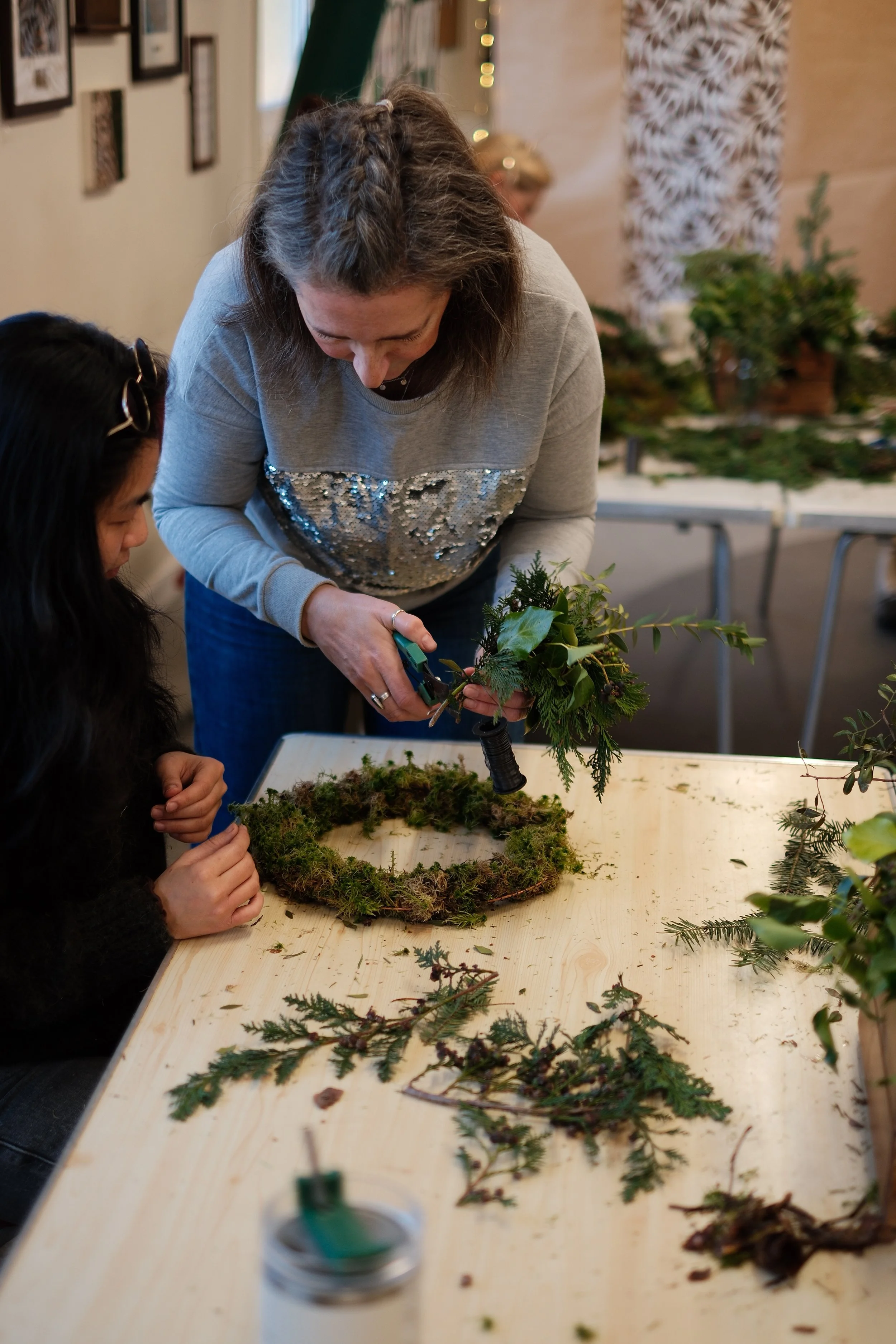 A student having a helping hand during the Christmas wreath class Cardiff