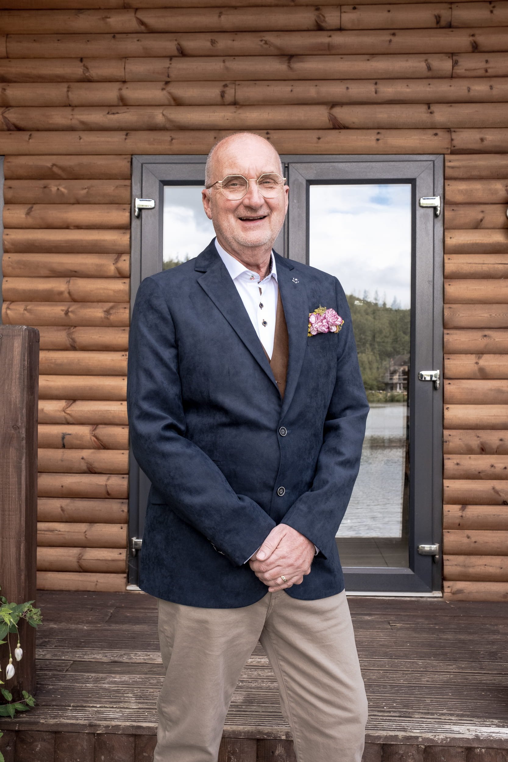The groom at same sex wedding is smiling wearing his jacket with purple pocket floral square