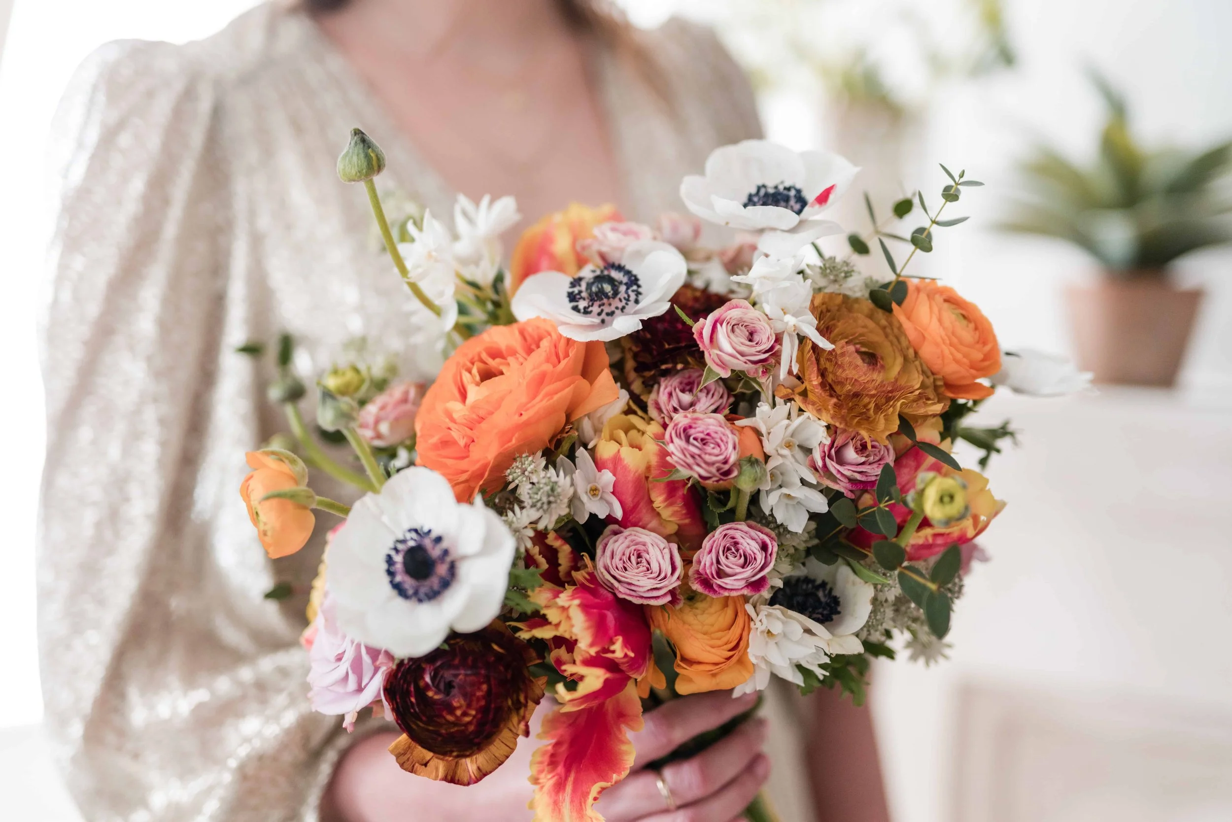 Bridal bouquet with Spring flowers in oranges and pinks with some white panda anemones and paperwhite narcissi