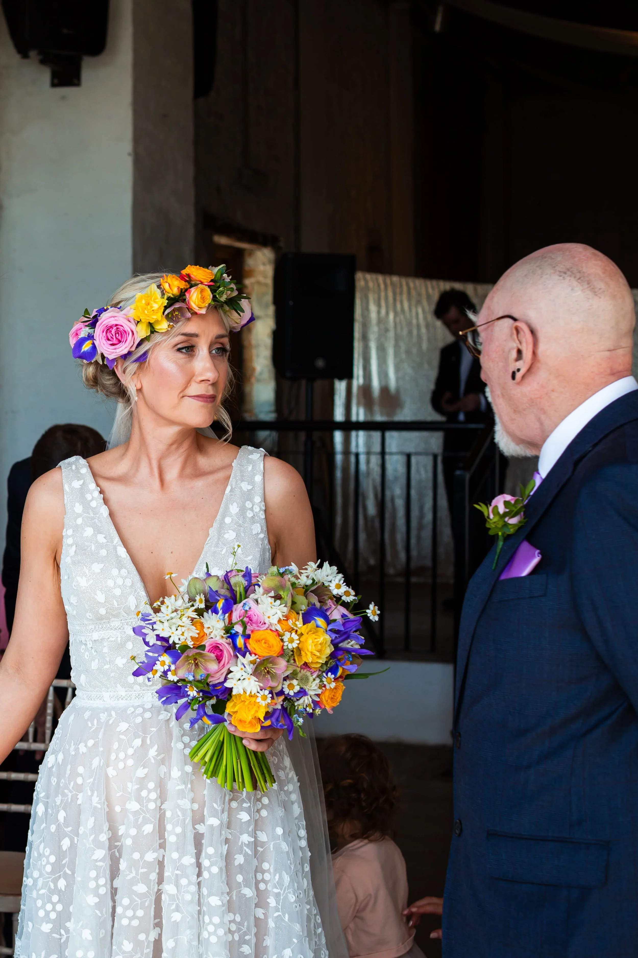 The spring wedding bride at Rosedew farm is wearing spring flower crown and holding her seasonal, colourful spring bridal bouquet holding her dad's hand at the wedding ceremony