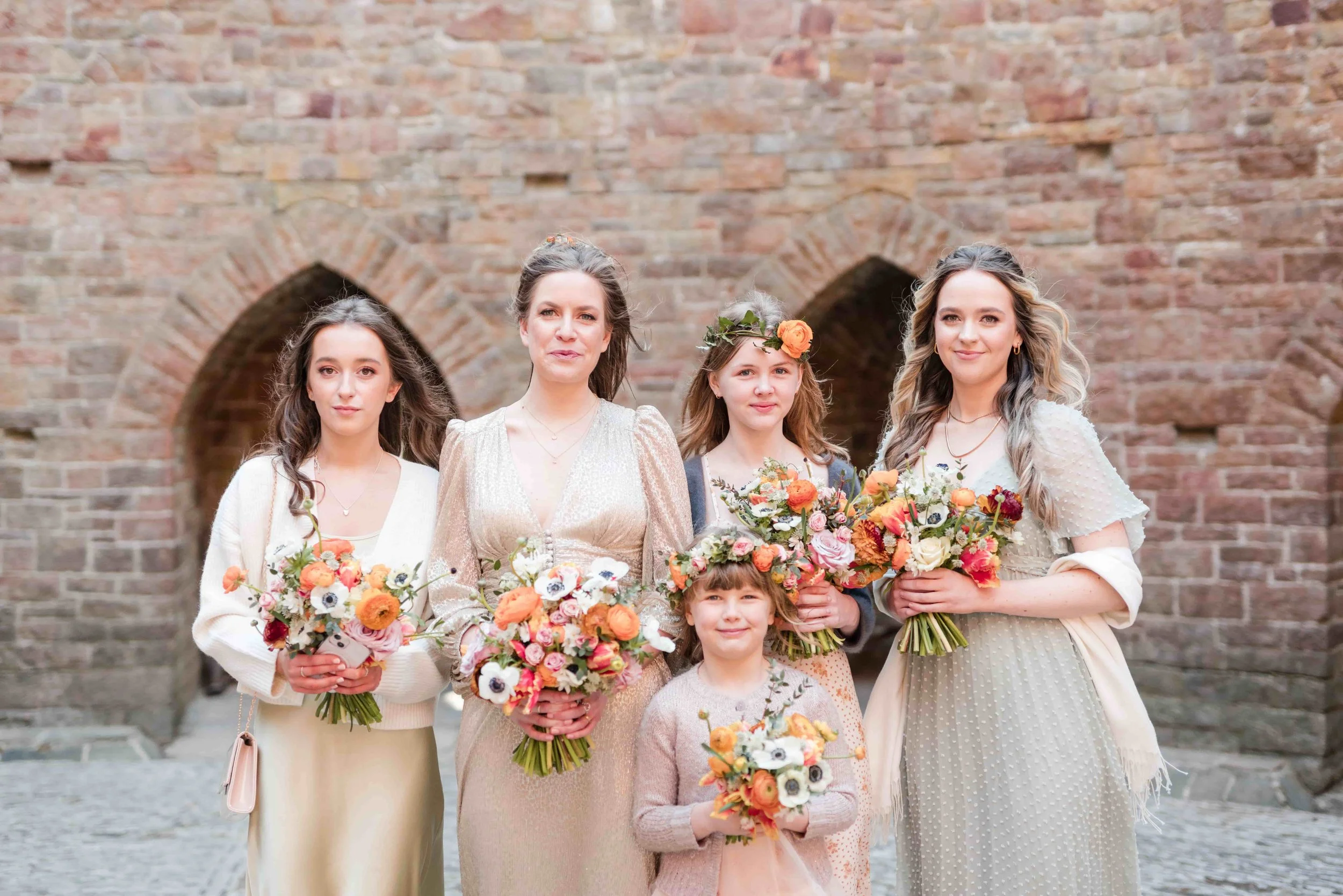 Bridal party with seasonal bright wedding flowers in orange, pink and white colours at Castel Coch