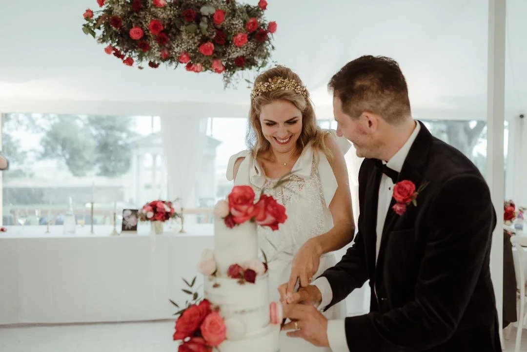 Cutting the cake with red, pink and burgundy flowers