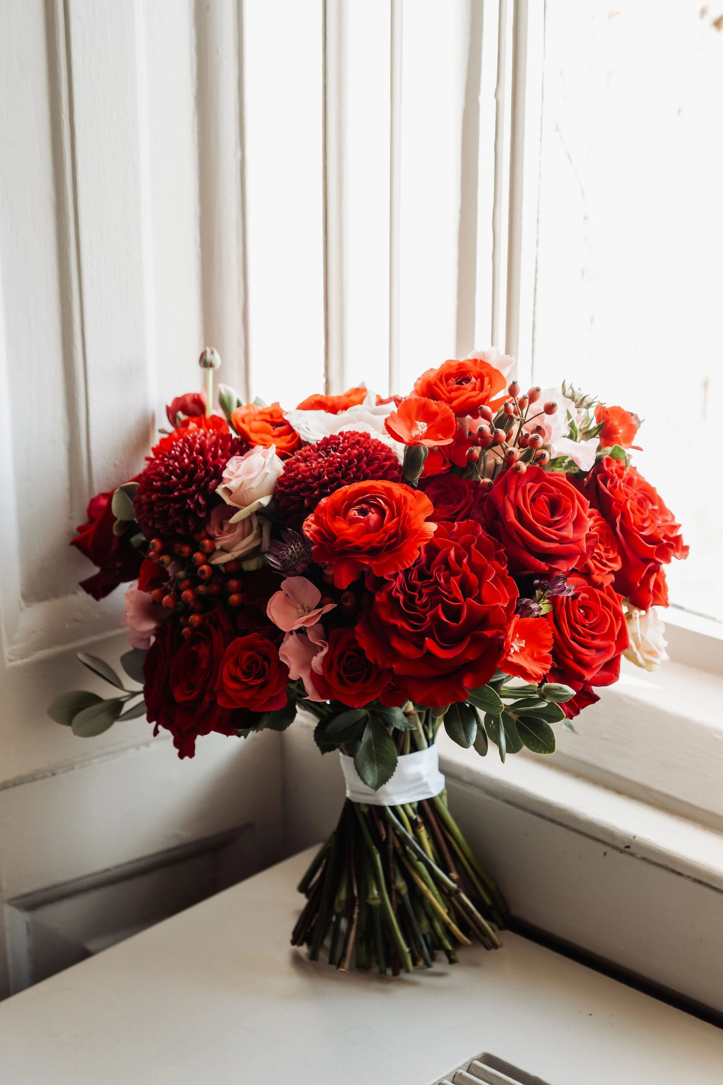 The bridal bouquet is propped in a window corner at Hensol Castle, you can see all the rich colours of burgundy, crimson and soft pink