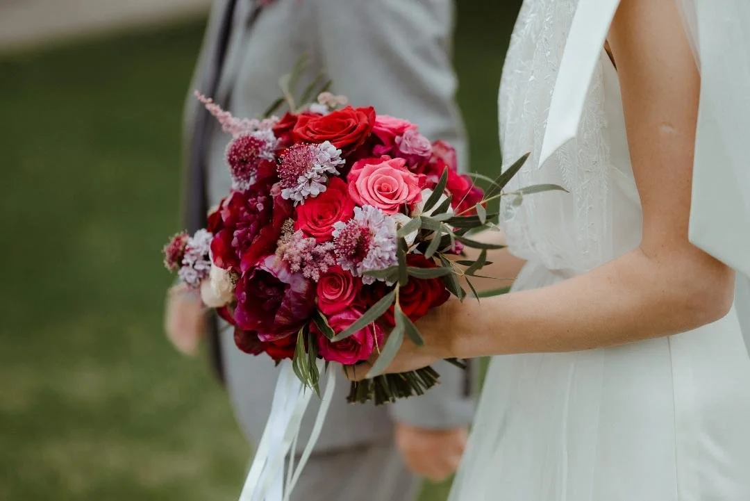 Bridal bouquet from the side angle with burgundy peonies, deep red roses, pink scabious, astilbe and roses