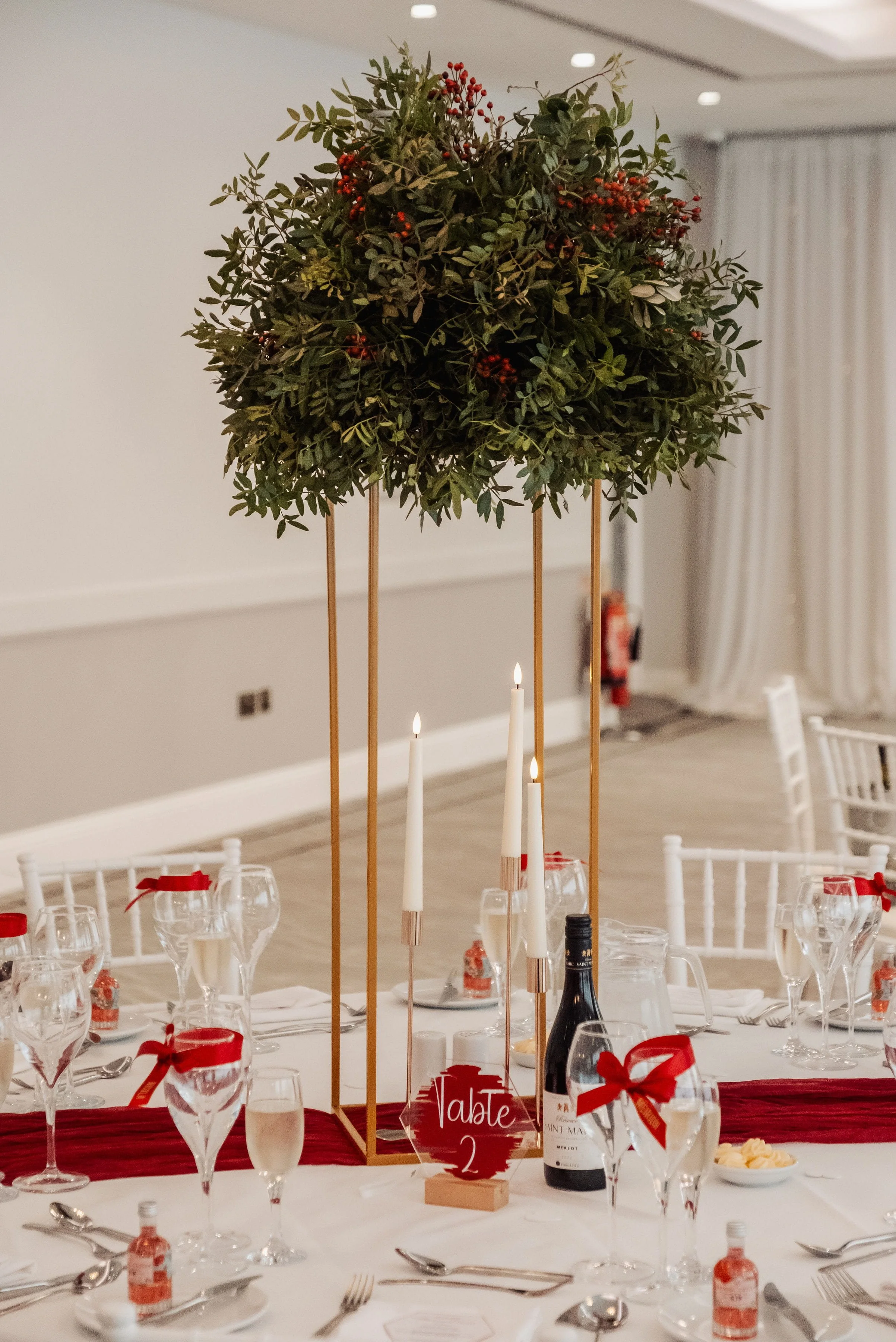 Domes full of dark green foliage and red rose hips stood on gold metal stands for Hensol Castle wedding