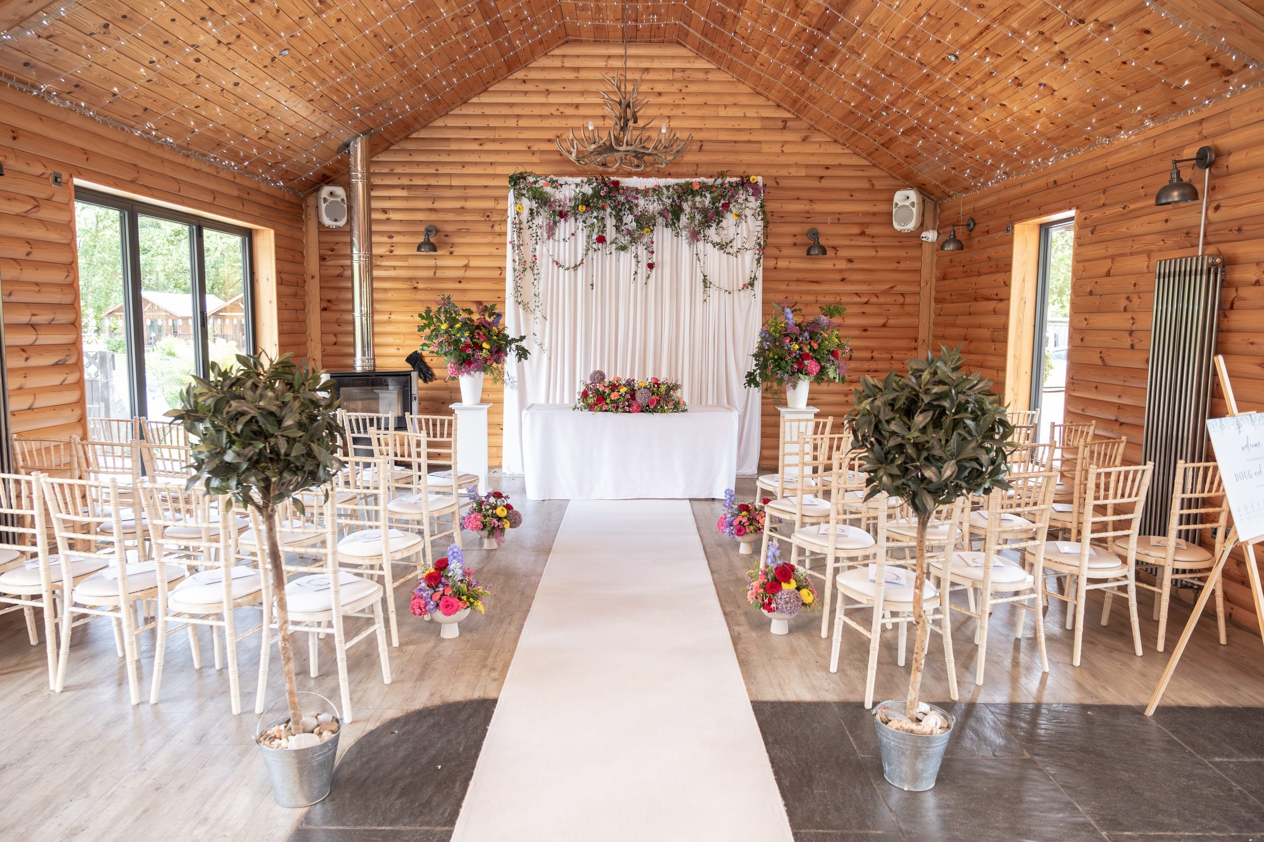 Colourful and bright wedding ceremony flowers with floral backdrop, bright registry table and aisle flowers