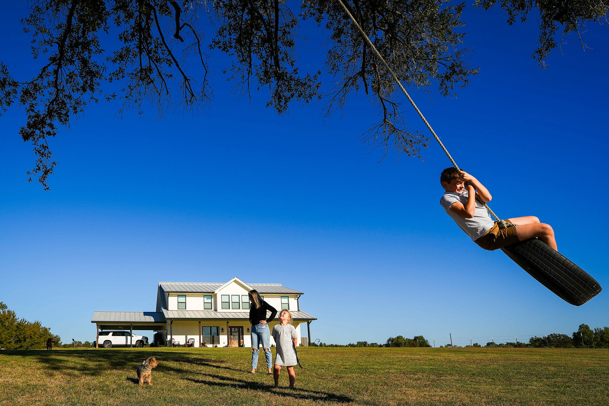 Reid Rolen, 9, plays on a tire swing as his sister Lyla, 5, and his mother Mandi Rolen look on Wednesday, Oct. 16, 2024, in Cuthand, Texas. Residents in the Sulphur River Basin will be impacted if the proposed Marvin Nichols Reservoir in northeast T